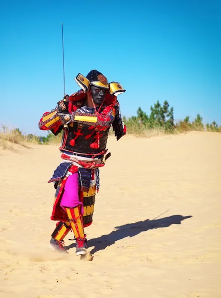 Man in samurai costume with sword running on the sand. — Stock Photo, Image