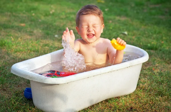 Un piccolo bambino felice bagnato nel bagno e che gioca in un bagno Foto Stock