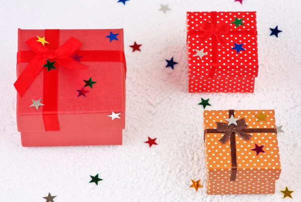 Bunte Weihnachtsgeschenke mit Sternen im Schnee — Stockfoto