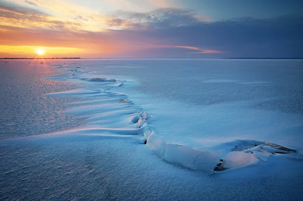 Vackra vinterlandskap med sjö, spricka och solnedgång himlen. — Stockfoto