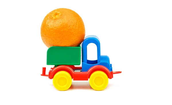 Küçük plastik renkli oyuncak kamyon ile bir büyük mandalina meyve sepeti — Stok fotoğraf