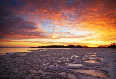 Günbatımı ateşli gökyüzü ile kış manzarası.