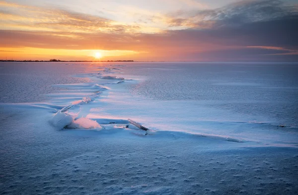 湖、亀裂、夕焼け空の美しい冬の風景. — ストック写真