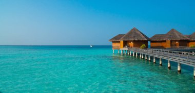 Tropikal Maldivler adasının inanılmaz geniş manzarası. Güneşli bir günde mavi gölü, turkuaz suyu ve palmiye ağaçları olan egzotik bir sahil. Tatil, tatil ve romantik balayı gezisi.