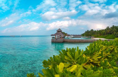 Tropikal Maldivler adasının inanılmaz geniş manzarası. Güzel gündoğumunda mavi göl, turkuaz su ve palmiye ağaçlarıyla egzotik plaj arka planı. Tatil, tatil ve romantik balayı gezisi.