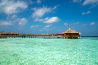 Maldivler cenneti manzarası. Su bungalovlu deniz burnu, güzel turkuaz deniz ve lagün suları, tropikal doğa. Egzotik tropikal ada plajı.