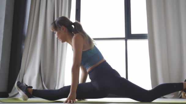 An attractive Japanese woman is sitting on a twine on the floor in a bright room with panoramic windows. fitness at home — Stock Footage An attractive Japanese woman is sitting on a twine on the floor in a bright room with panoramic windows. fitness at home Royalty Free Stock Video