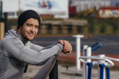 Otuz yaşında güçlü bir atlet yatay çubuklarda dikilip kameraya bakıyor. Spor yaşam tarzı..
