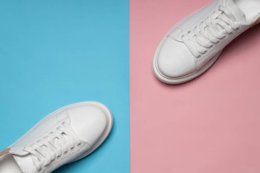 Mavi ve pembe arka planda beyaz deri ayakkabılar. Bir çift beyaz spor ayakkabısı ya da fotokopi alanı olan spor ayakkabısı. düz yat