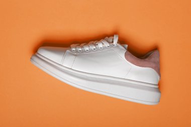 Mavi ve turuncu arka planda beyaz deri ayakkabılar. Bir çift beyaz spor ayakkabısı ya da fotokopi alanı olan spor ayakkabısı. düz yat