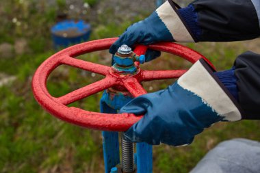 Teknisyen, deniz aşırı petrol ve gaz platformunun kontrol işlemleri için elle top valfini açarken ya da kapatırken ellerini lastik eldivenlerle tut.