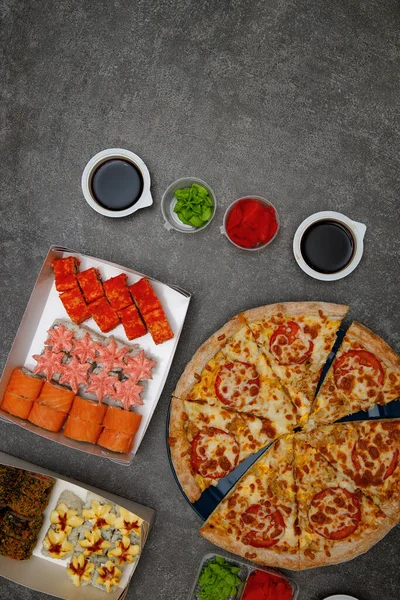 Beautiful and delicious sushi and pizza on a gray concrete background. Flat lay