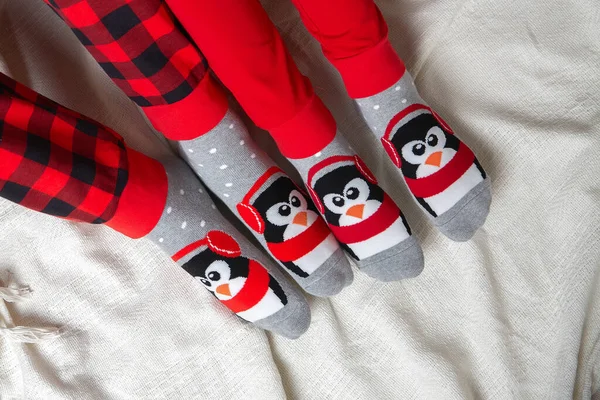 Nohy ve vánočních ponožkách na bílé dece. Pár, sedících u přikrývky, si uvolněně ohřívá nohy ve vlněných ponožkách. Koncept zimních a vánočních svátků — Stock fotografie