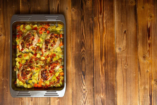 Fertiges Hühnerfilet auf einem Backblech mit Oliven und Gemüse auf einem Holztisch, Draufsicht, Kopierraum — Stockfoto