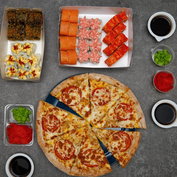 Pizza and sushi rolls on a gray concrete background. Food background.the view from the top.