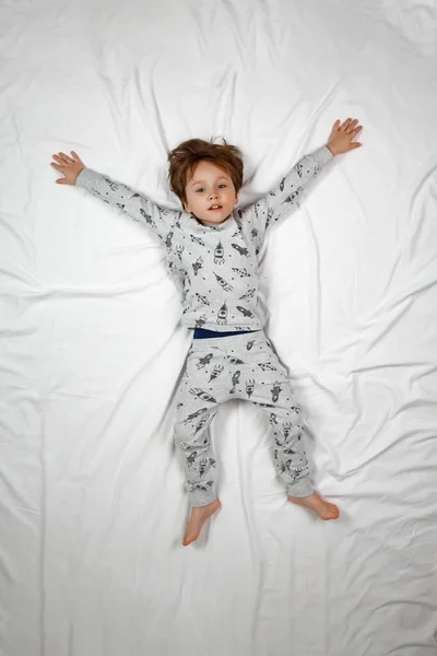 Lustiger Junge spielt im Bett. Blick von oben — Stockfoto