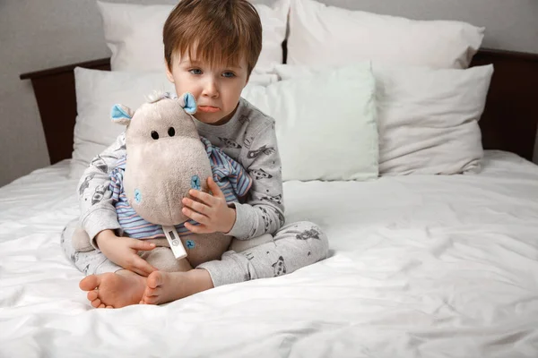 Sick five-year-old boy in a medical protective mask uses a tablet computer while lying on a bed at home . The concept of quarantine and epidemic coronavirus strain. — Stock Photo, Image