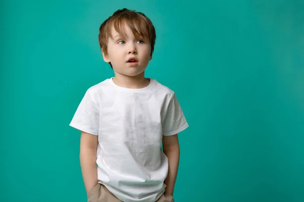 Cute boy of five looks away in surprise isolated on a green background — Stock Photo, Image