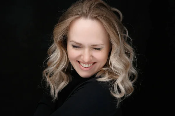 Beautiful portrait of a young smiling woman. Blonde with curly hair healthy skin and natural makeup on a black background — Stock Photo, Image