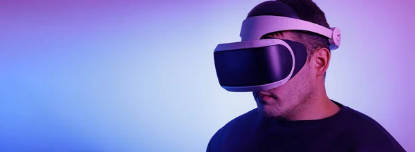 Un hombre de treinta años con gafas de realidad virtual jugando videojuegos con un auricular de realidad virtual Fashionable Neon Tinted. Copiar espacio —  Fotos de Stock