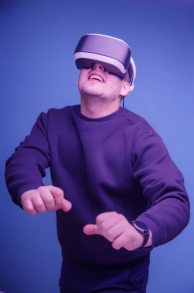 Un hombre juega con las manos levantadas con gafas de realidad virtual y extiende los brazos delante de él. Pintura tintada azul —  Fotos de Stock