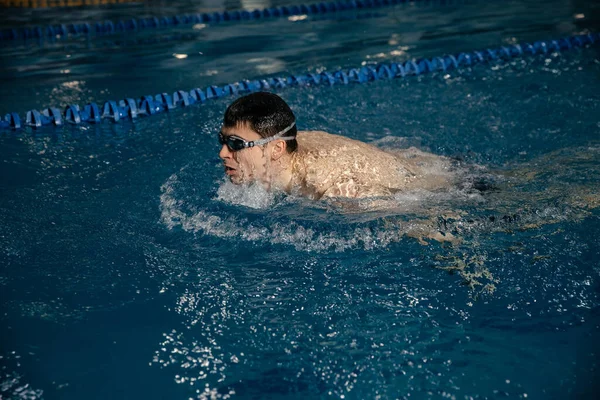 Güçlü atletik kaslı beyaz erkek kelebek yüzer. Sporcuları yarışmalara hazırlama kavramı