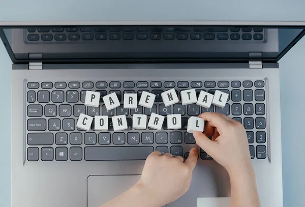 On the keyboard of the laptop there are wooden white cubes with the text \