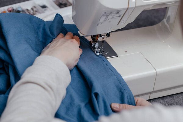 Sewing. A girl sews clothes at home on a sewing machine, ecology. Doing your favorite thing, hobbies, recycling.