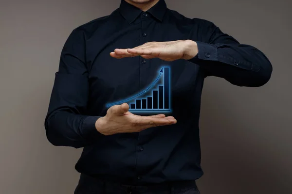 Businessman holds the growth chart in the palm of his hand. Business development and planning for success and growth. Concept of a plan to improve performance in your business