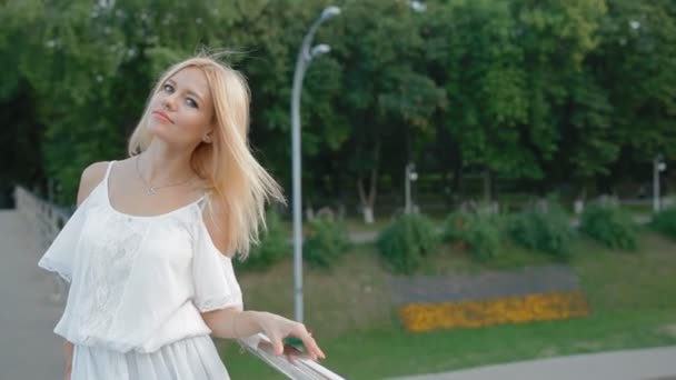 Mujer rubia joven en vestido blanco claro al aire libre — Vídeos de Stock