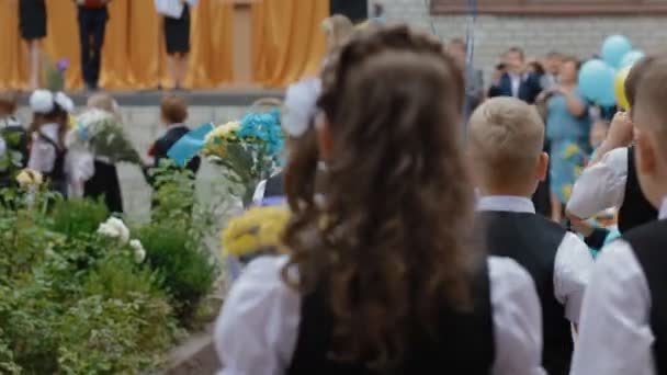 DNEPR, UCRÂNIA - 1 de setembro de 2015: Os primeiros ex-alunos que seguram buquê de flores vão ao seu lugar na festa do primeiro sino . — Vídeo de Stock