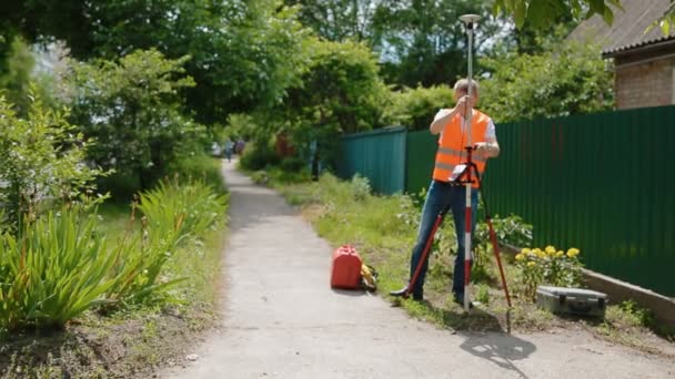 Trabajador prepara dispositivo geodésico para la topografía — Vídeo de stock