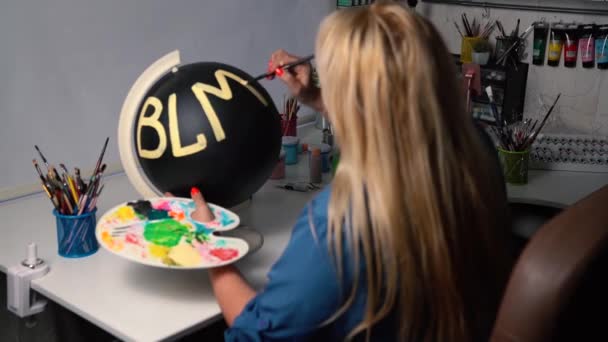 Огрядна жінка малює символ BLM на чорній кулі. — стокове відео