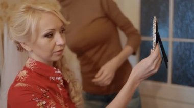 Genç kadın aynaya bakmak ve onun hairdress değerlendirmek