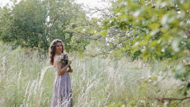 Young woman stand in the field with bouquet — Stock Video