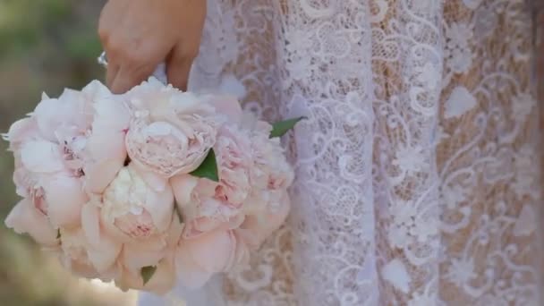 Невеста держит свадебный букет, жених трогает ее руку — стоковое видео