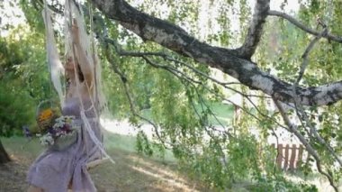 Genç kadın sallanmak ağacının gölgesinde.