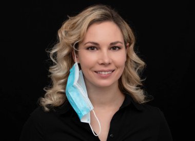 Güzel sarışın bir kız maskesini çıkarırken gülüyor.