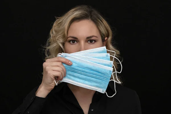 Bir kız yüzünü karanlık bir arka planda tıbbi maskelerle kapatıyor.