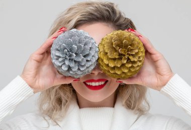 Güzel gülüşü olan güzel bir manken iki büyük kozalak tutuyor.