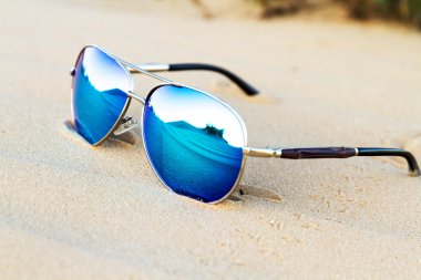 Çölde kum üzerinde güneş gözlüğü.