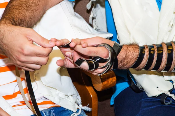 Um judeu ortodoxo religioso com braço-tefillin em sua mão esquerda  . — Fotografia de Stock