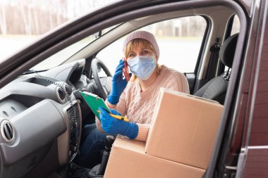 Coronavirus. Kurye elinde tıbbi lastik eldivenlerle dolu bir karton kutu tutuyor. Karantinaya alın. Eve teslim.