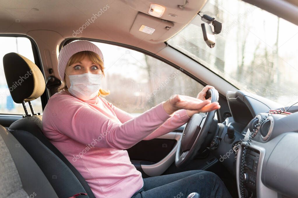 A woman in a medical mask rides in a car during the covid-19 coronavirus. She raised her hand.