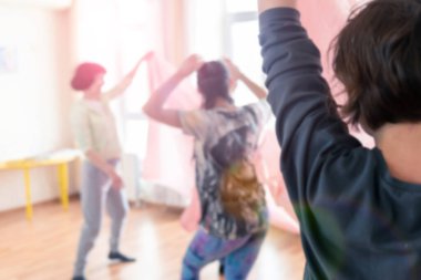 Odaklanma. Kadınlar büyük pencereli spor salonunda rahatlar. Büyük şeffaf kumaşlar ve perdeler. Meditasyon yapıyor ve yoga yapıyor..