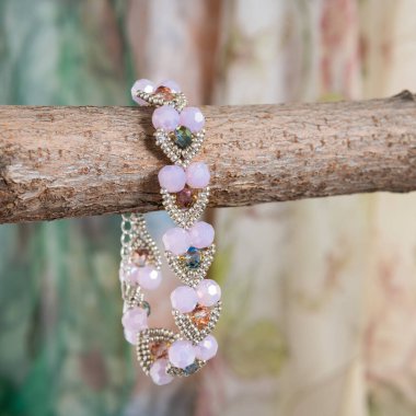 Arka planda eller tarafından yapılan farklı renkte boncuklardan yapılmış bilezik.