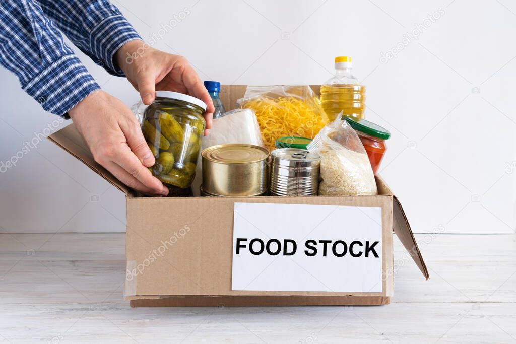 Box with food stock. Cardboard box with butter, canned food, cereals and pasta. Reserve.
