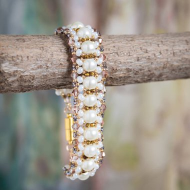 Arka planda eller tarafından yapılan farklı renkte boncuklardan yapılmış bilezik.