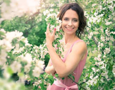 Kadın çiçek açan bir bahçede yürüyor. Koyu saçlı bir kadının portresi. Elma ağacı baharda açar.