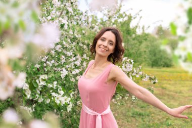 Güzel bir kadın çiçek açan bir bahçede yürüyor. Koyu saçlı bir kadının portresi. Elma ağacı baharda açar.